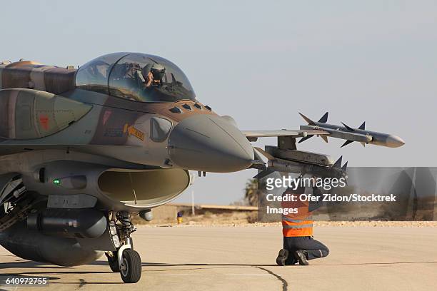 ground crew member checks the rafael python missile on a f-16i sufa jet. - airline crew member stock-fotos und bilder