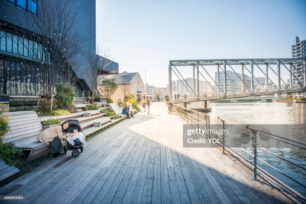 A Baby and Mother along the river on wooden deck.