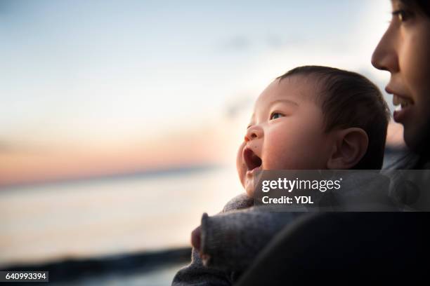 a baby and mother in the sunset ocean. - moment of silence stockfoto's en -beelden