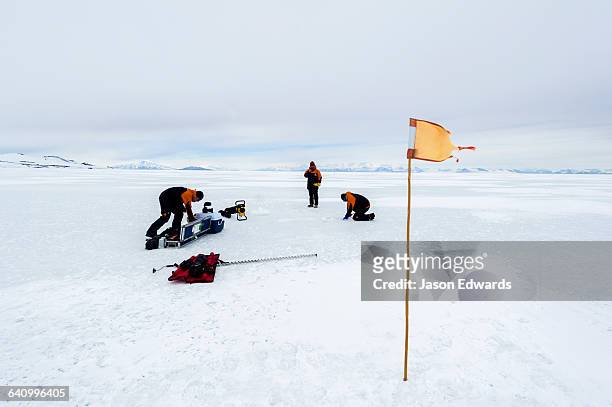 researchers drill core samples from the sea ice to collect extremophiles from beneath the ice to study. - extremophile stock pictures, royalty-free photos & images