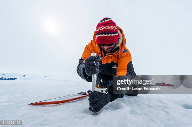 researchers drill core samples from the sea ice to collect extremophiles from beneath the ice to study. - extremophile stock pictures, royalty-free photos & images