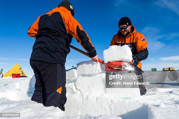 antarctic base staff cutting ice bricks to make a kitchen wall on the sea ice during a survival course. - ross ice shelf stock pictures, royalty-free photos & images