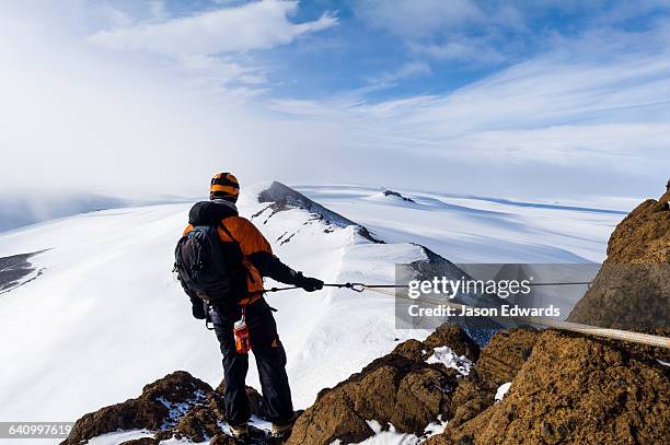 mountain climbers using climbing ropes and carabiner to scale a cliff overlooking the ross ice shelf. - ross ice shelf stock pictures, royalty-free photos & images