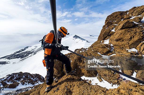mountain climbers using climbing ropes and carabiner to scale a cliff overlooking the ross ice shelf. - ross ice shelf stock pictures, royalty-free photos & images