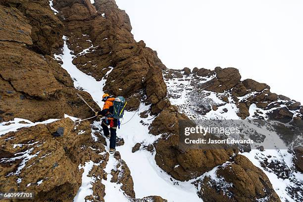 mountain climbers using climbing ropes to scale a cliff overlooking the ross ice shelf. - ross ice shelf stock pictures, royalty-free photos & images