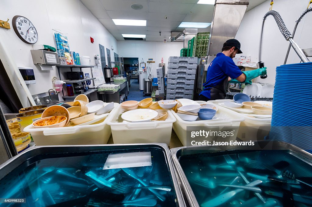 A dishwasher cleans utensils in an Antarctic base kitchen after Thanksgiving.