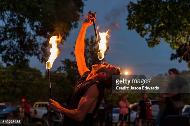 a fire performer dazzles the crowd at an open-air market by swallowing a flaming baton. - fun northern territory stock pictures, royalty-free photos & images