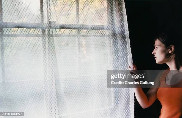 woman looking out of window - vouyer stock pictures, royalty-free photos & images