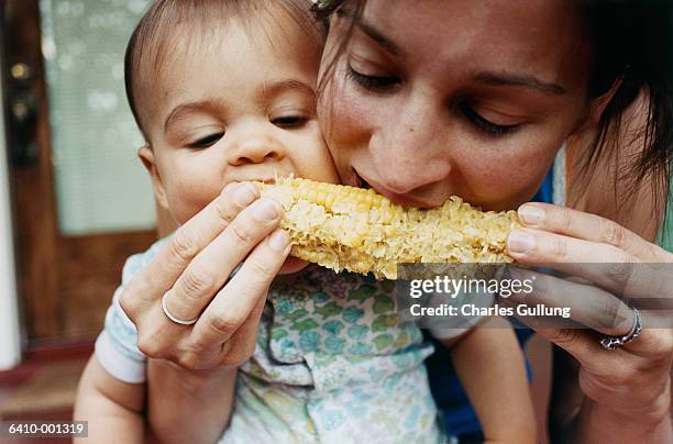 mother and baby eating corn - essen mund benutzen stock-fotos und bilder