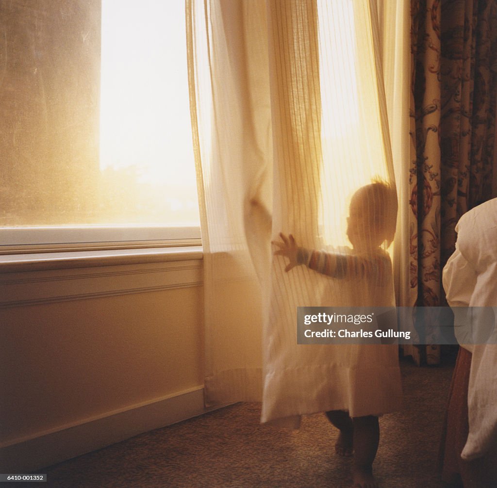 Toddler Hiding behind Curtain