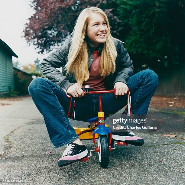 teenage girl riding tricycle - tricycle stock-fotos und bilder