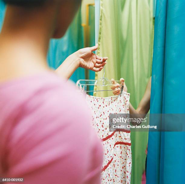 girl passing skirt to friend - girl changing room shop stock-fotos und bilder