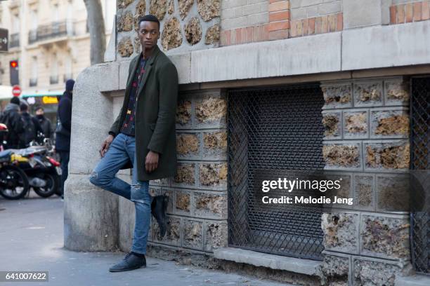 Oliver Kumbi wears a forest green coat and jeans outside the Lemaire show at Palais de la Femme show on January 18, 2017 in Paris, France.