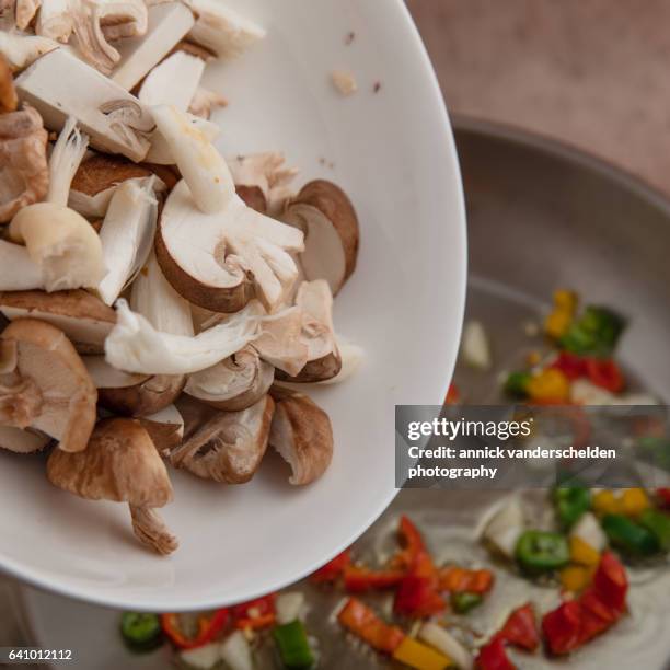 adding mushrooms to fried chili pepper. - adding chilli stock pictures, royalty-free photos & images