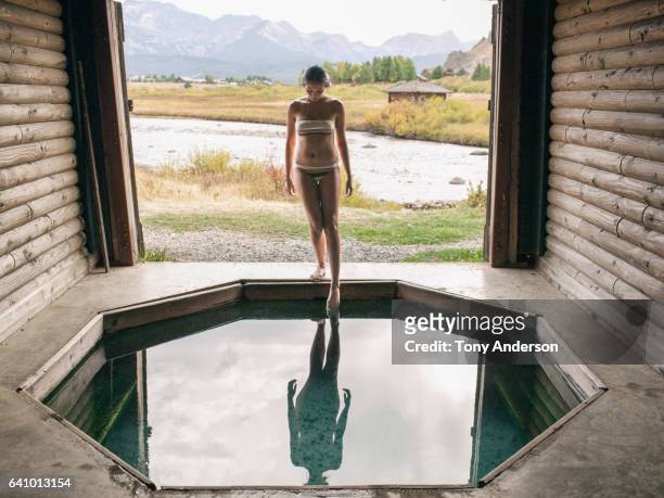 Young woman at hot tub in dramatic mountain landscape