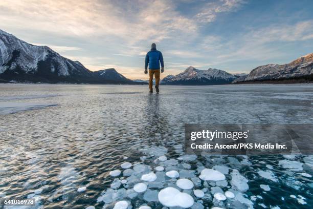 man stands on frozen lake surface, looks towards mountains - shoes top view stock pictures, royalty-free photos & images