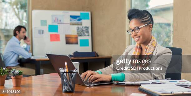 confident businesswoman uses laptop computer in the office - admin assistant stock pictures, royalty-free photos & images