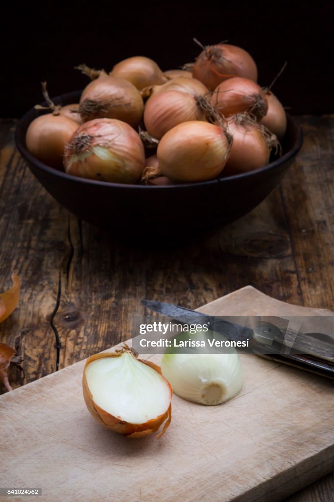 Onions on dark wood, cutting board and knife