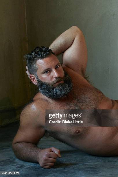 bearded shirtless man lying concrete floor - behaart stock-fotos und bilder