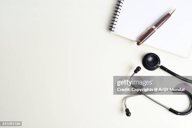 top view of stethoscope and writing pad on white desk in doctors office - doctors office no people stock pictures, royalty-free photos & images