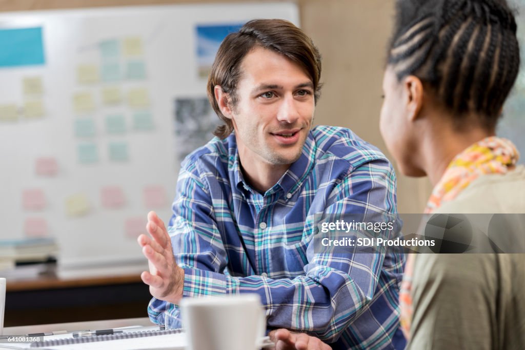 Caucasian male business professional talks with female associate