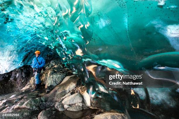 woman with blue coat inside a crystal ice cave in winter. iceland - crystal caves stock-fotos und bilder