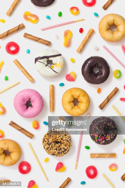 Colourful glazed donuts, candy and snacks on white background.