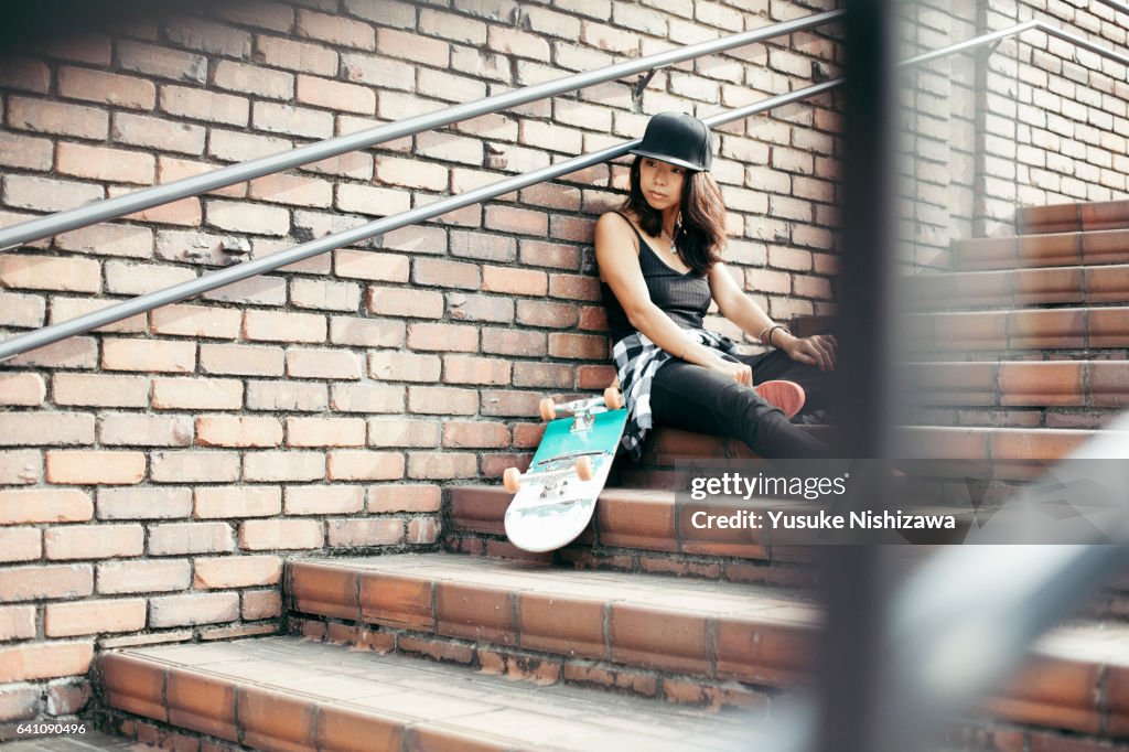 The woman who sits down near skateboarding