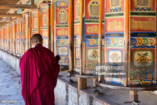 a monk is walking and turning huge and colorful prayer wheels in labrang monastery - tibetansk buddhism bildbanksfoton och bilder