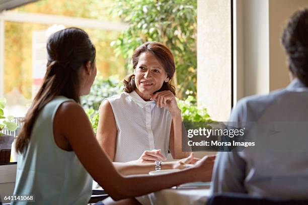 businesswoman listening to colleague in restaurant - women meeting lunch stock pictures, royalty-free photos & images