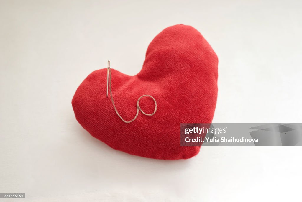Red pillow shaped heart with a needle and thread