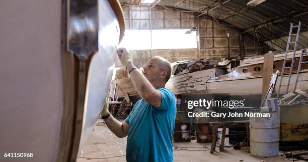 mature male boat builder working in workshop - shipyard stock-fotos und bilder