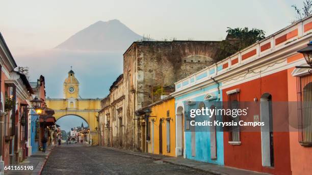 agua volcano and arco de santa catalina (santa catalina arch) in antigua guatemala - antigua guatemala stock pictures, royalty-free photos & images