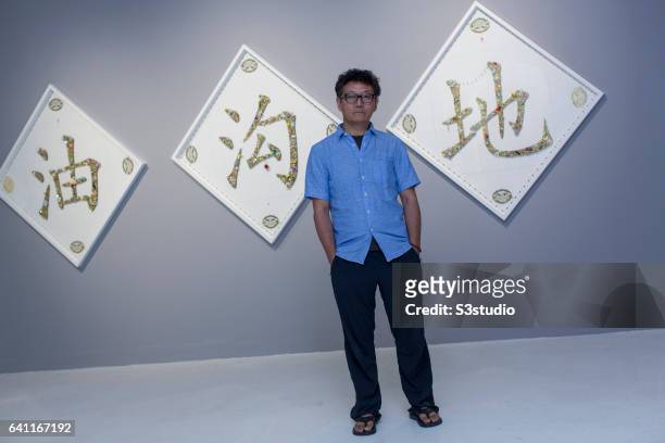 Artist Gonkar Gyatso poses in front of one of his works during the Pop Phraseology exhibition at the Pearl Lam Galleries in Hong Kong on 17 Sept 2014.