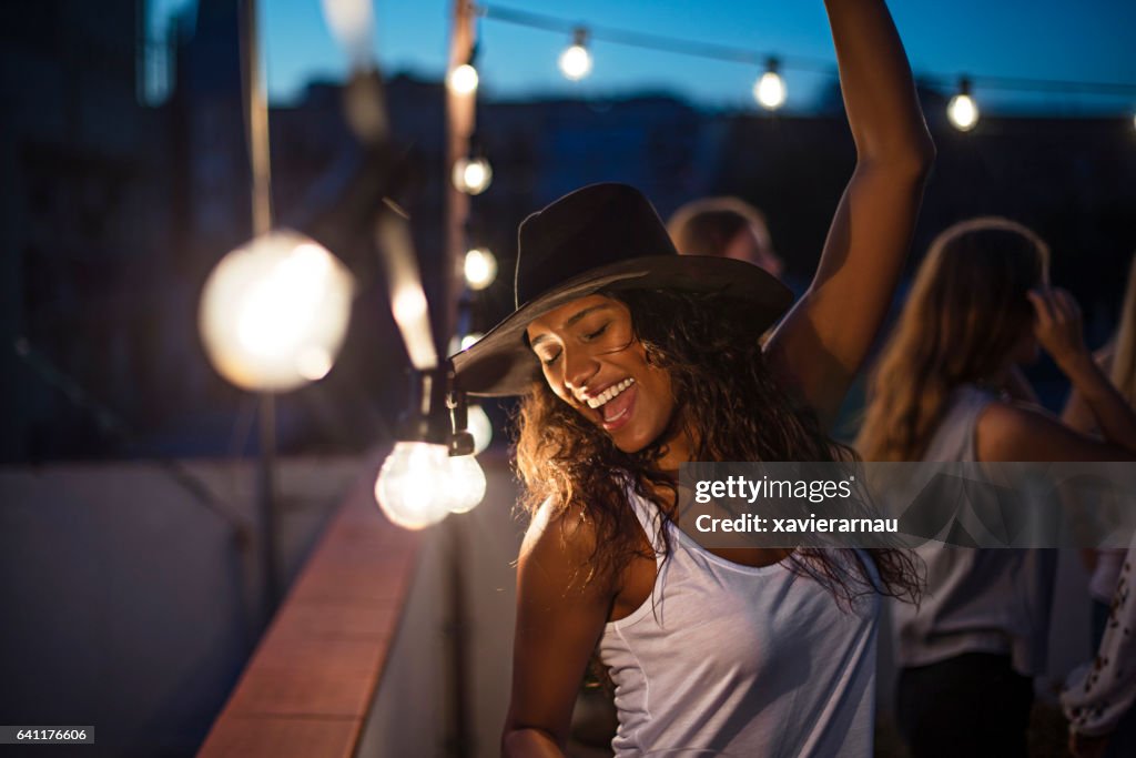 Cheerful woman dancing during terrace party