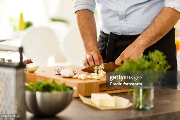chef slicing garlic on cutting board - alho imagens e fotografias de stock