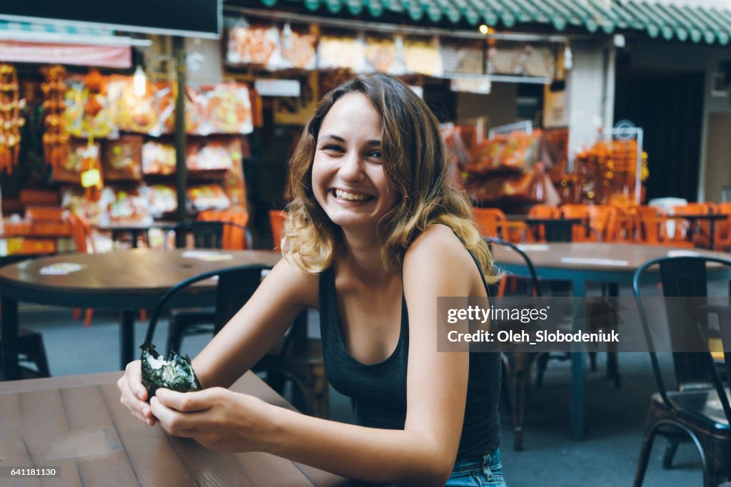 Woman eating in Chinatown district in Singapore