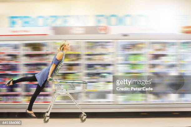 woman riding shopping trolley down aisle - action hero stock pictures, royalty-free photos & images
