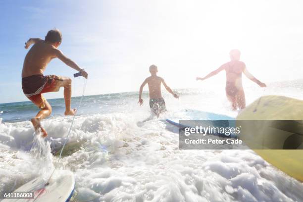 three friends playing in sea with bodyboards - beach holiday uk stock pictures, royalty-free photos & images