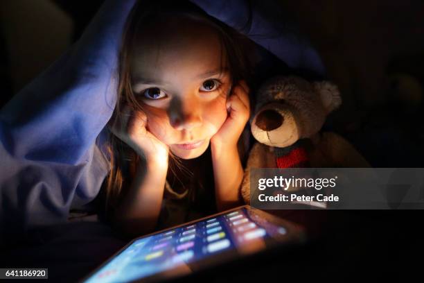 girl in bed at night looking at tablet - parental control stock-fotos und bilder