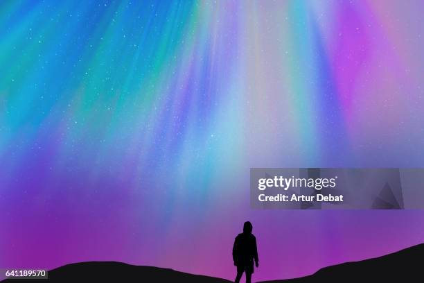 silhouette of a guy with the beautiful colorful northern lights falling from the sky in iceland in a stunning clear and nice lights with the sky full of stars. aurora borealis. - psychedelic trip stock pictures, royalty-free photos & images