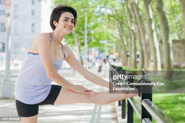 female runner stretching in park - running shorts stock pictures, royalty-free photos & images