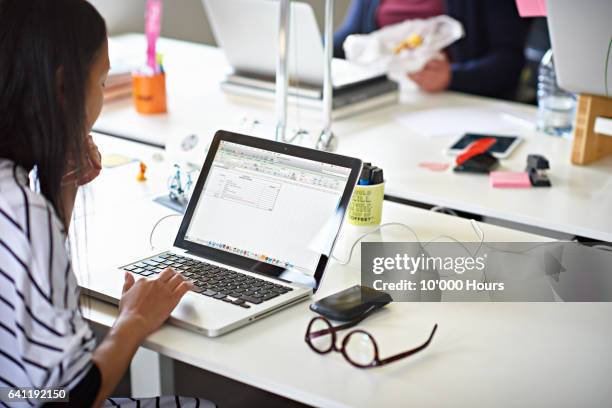 businesswoman working on a laptop in hot desking start-up office - hot filipina women stockfoto's en -beelden