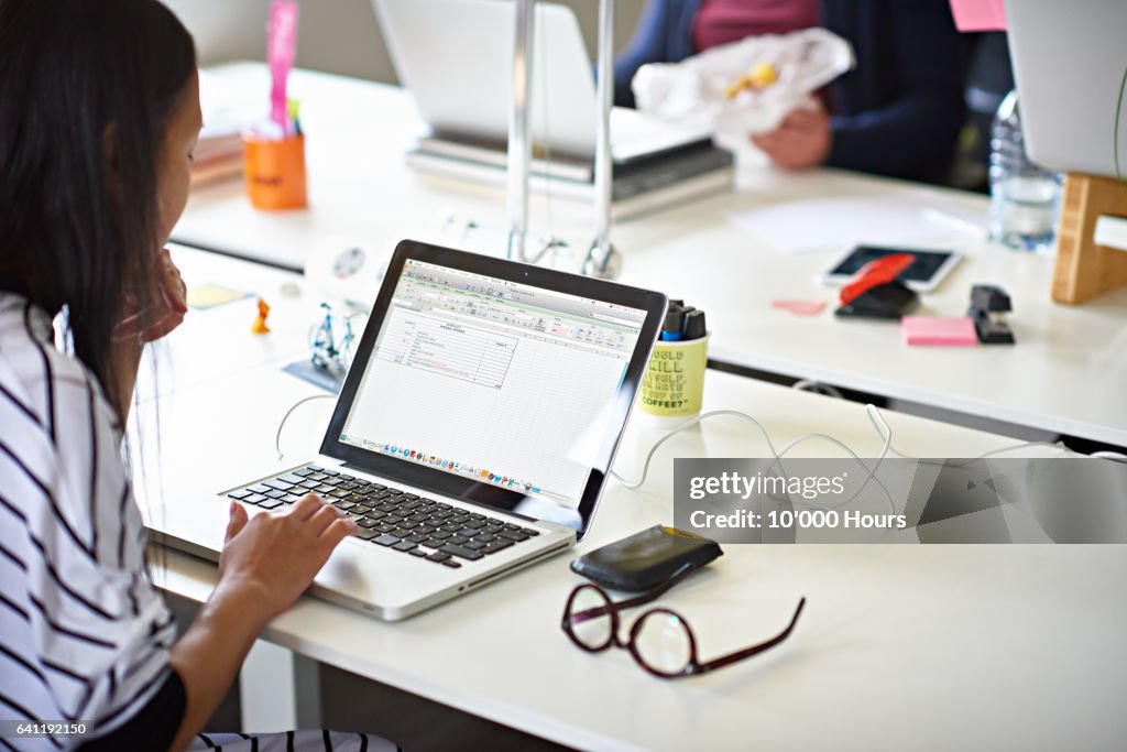 Businesswoman working on a laptop in hot desking start-up office