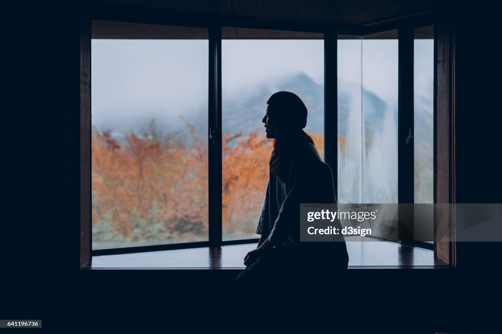 Beautiful young girl resting on windowsill looking through window