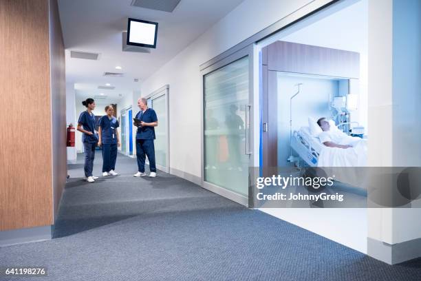 medical staff talking in corridor, patient in bed in ward - hospital room stock pictures, royalty-free photos & images