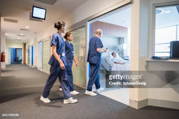 ärzteteam eingabe krankenstation, wo männliche patient liegt, im bett - krankenstation stock-fotos und bilder