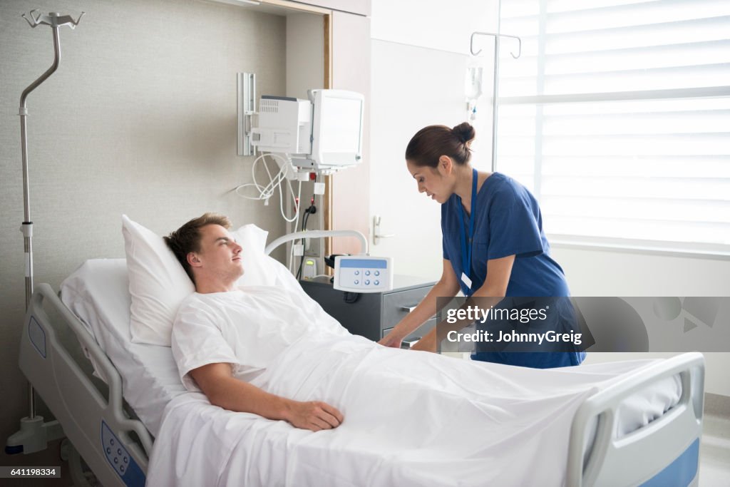 Young man in hospital bed with nurse by his side