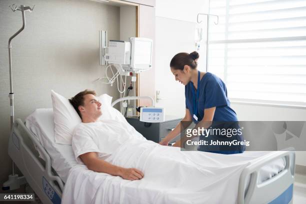 young man in hospital bed with nurse by his side - aboriginal man imagens e fotografias de stock