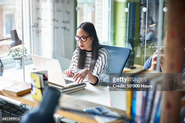 woman using laptop at desk. - philippines women stock pictures, royalty-free photos & images
